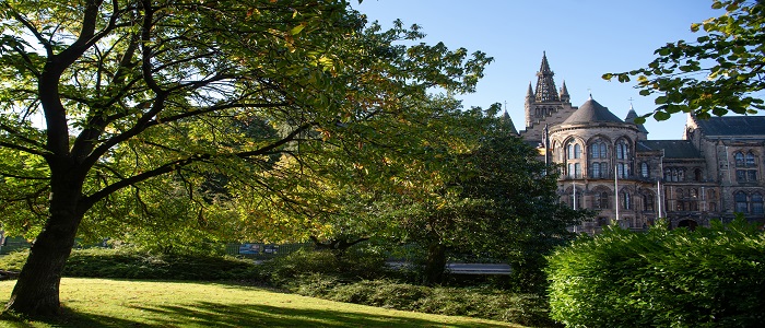 The Gilbert Scott Building behind some leafy green trees