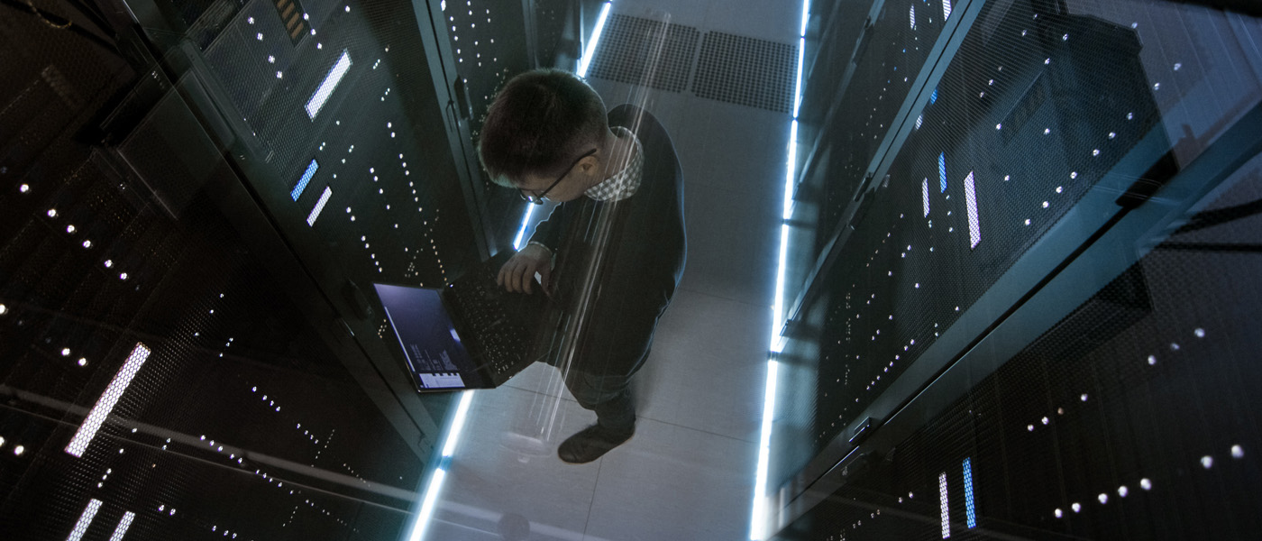 A man working with computer servers and a laptop