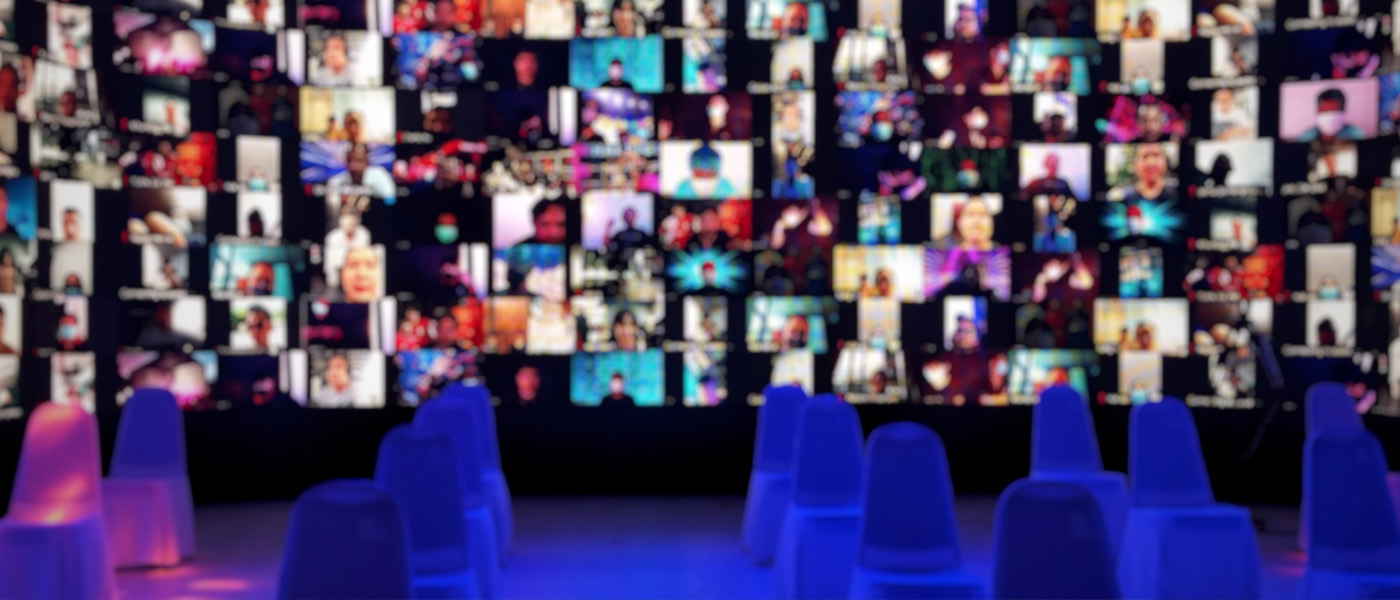 An image of a video wall of participants, tables and chairs at a summit.