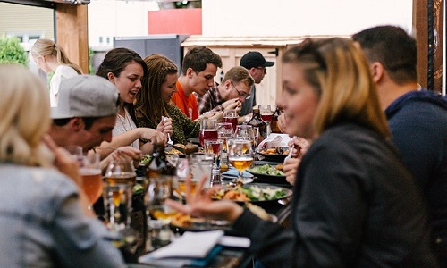 Group of diners sitting at a table full of food and drink