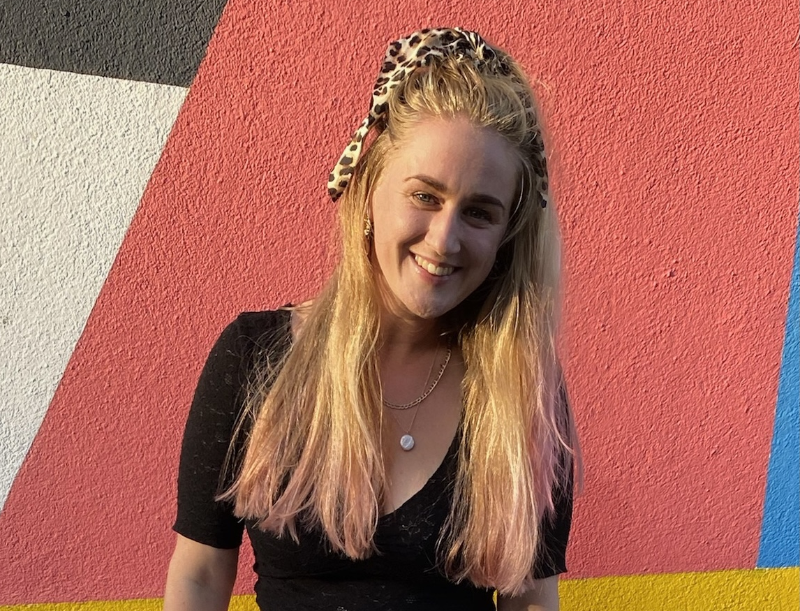 UofG 4th Year Medical Student Caitlin standing in front of a wall smiling.