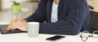 Photo of man in a wheelchair sitting at a desk with laptop, mug, and spectacles