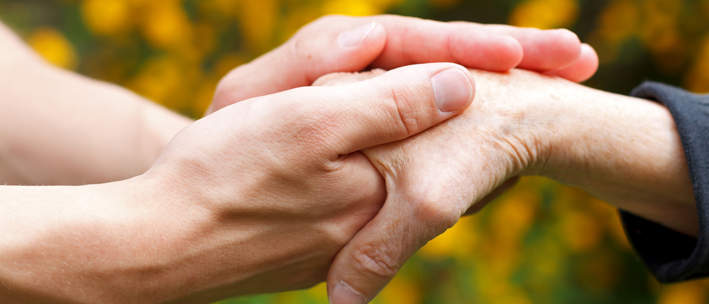Photo of carer holding the hands of a loved one