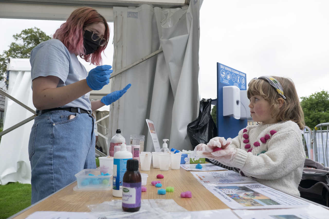 A young girl is following instructions from the stall holder on how to make her own slime