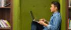 Photo of male student or researcher in library with laptop and books 