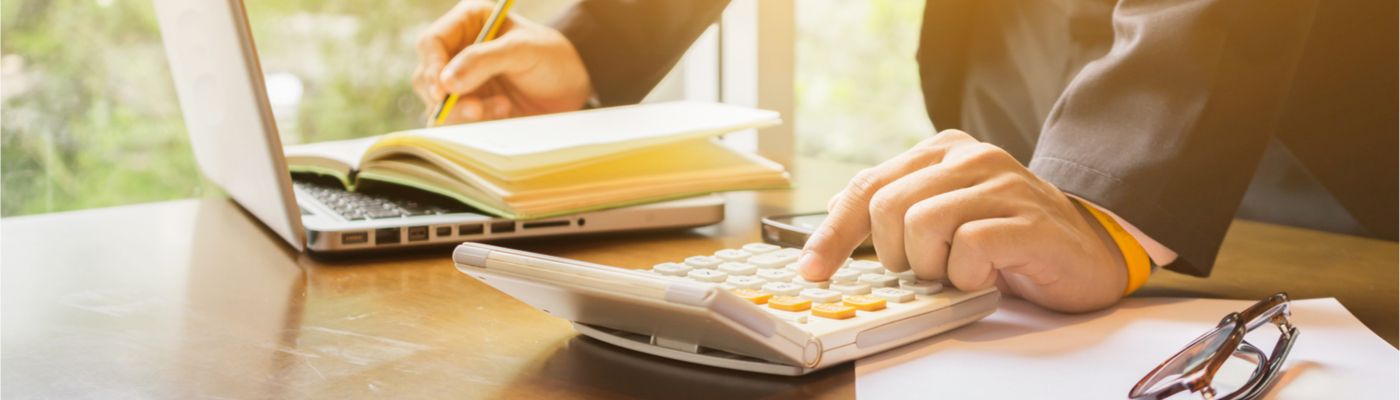 Image of an individual using a calculator and writing in a notebook