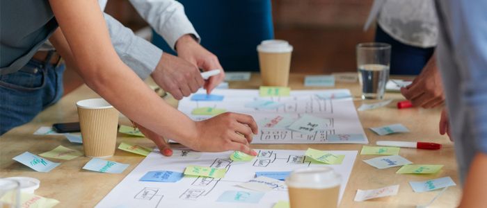 Image of a brainstorming session with individuals arranging post it notes on a table