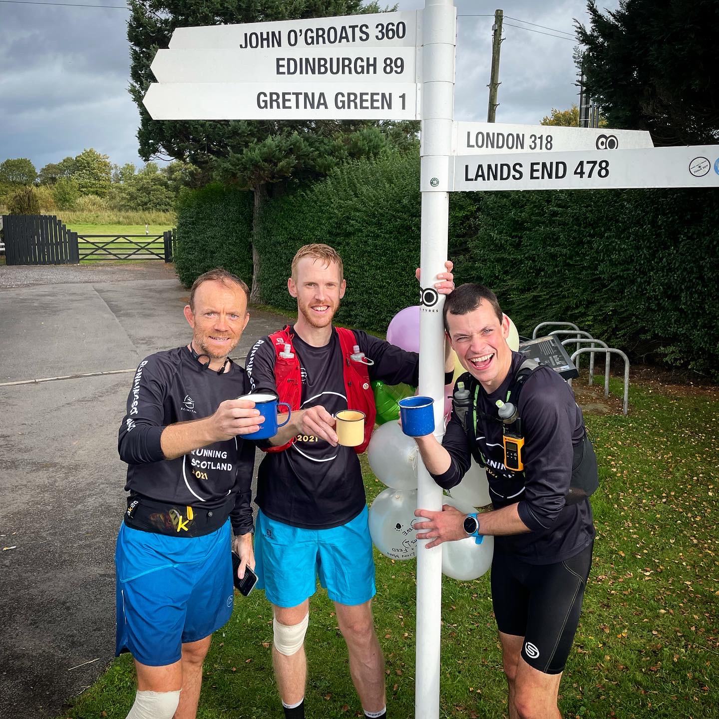 Image of three dental fellows on completion of a run, next to a location pole.