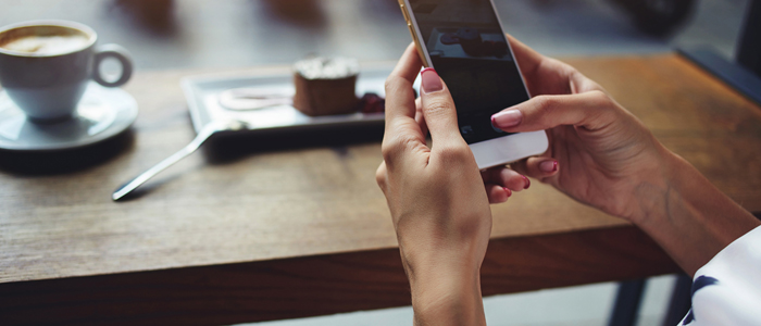 Photo of person sitting in cafe drinking coffee with mobile phone