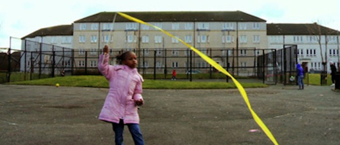 Image of a young girl playing with a ribbon in a car park