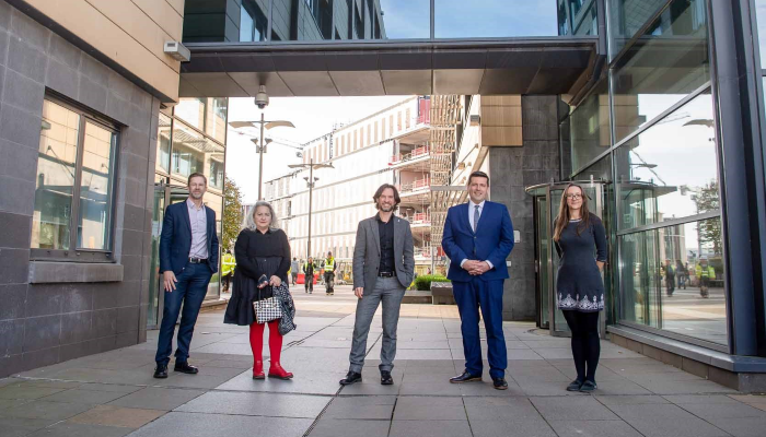 Jamie Hepburn stood outside the SGDB with Professor Carl Goodyear, Professor Stefan Siebert, Caroline Aylott, Alan McGinley, and Angela Donaldson-Bruce. 