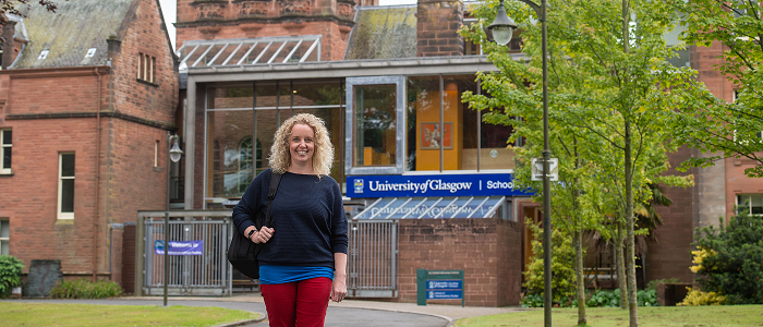 A student standing in front of the Rutherford building at Dumfries Campus