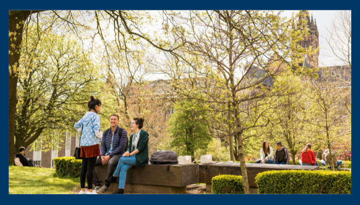 Outside the Fraser Building students sit and chat.  Image chosen to depict the linkage of outdoors and social with wellbeing