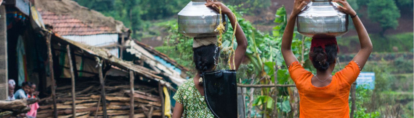 2 women carrying water containers on the heads