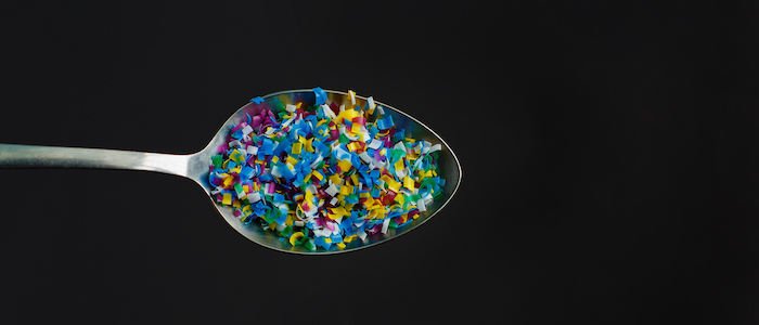 colourful microplastics in a spoon, black background
