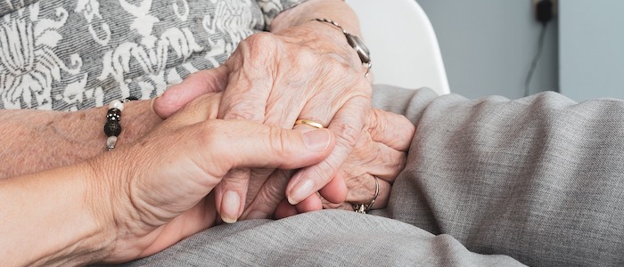 A younger hand holding an elderly hand