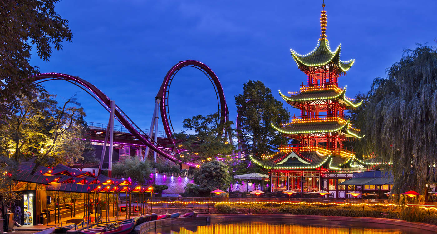 The old amusement park in Tivoli Gardens lit up at nighttime [Photo: Shutterstock]
