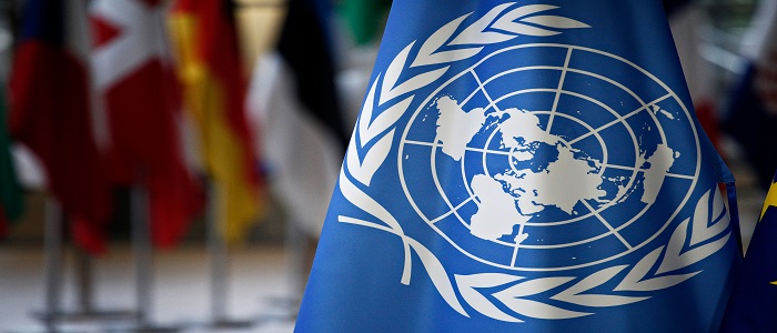 Un flag with blurred images of EU flags in the background