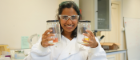 A student in the lab holding jars with experiments inside