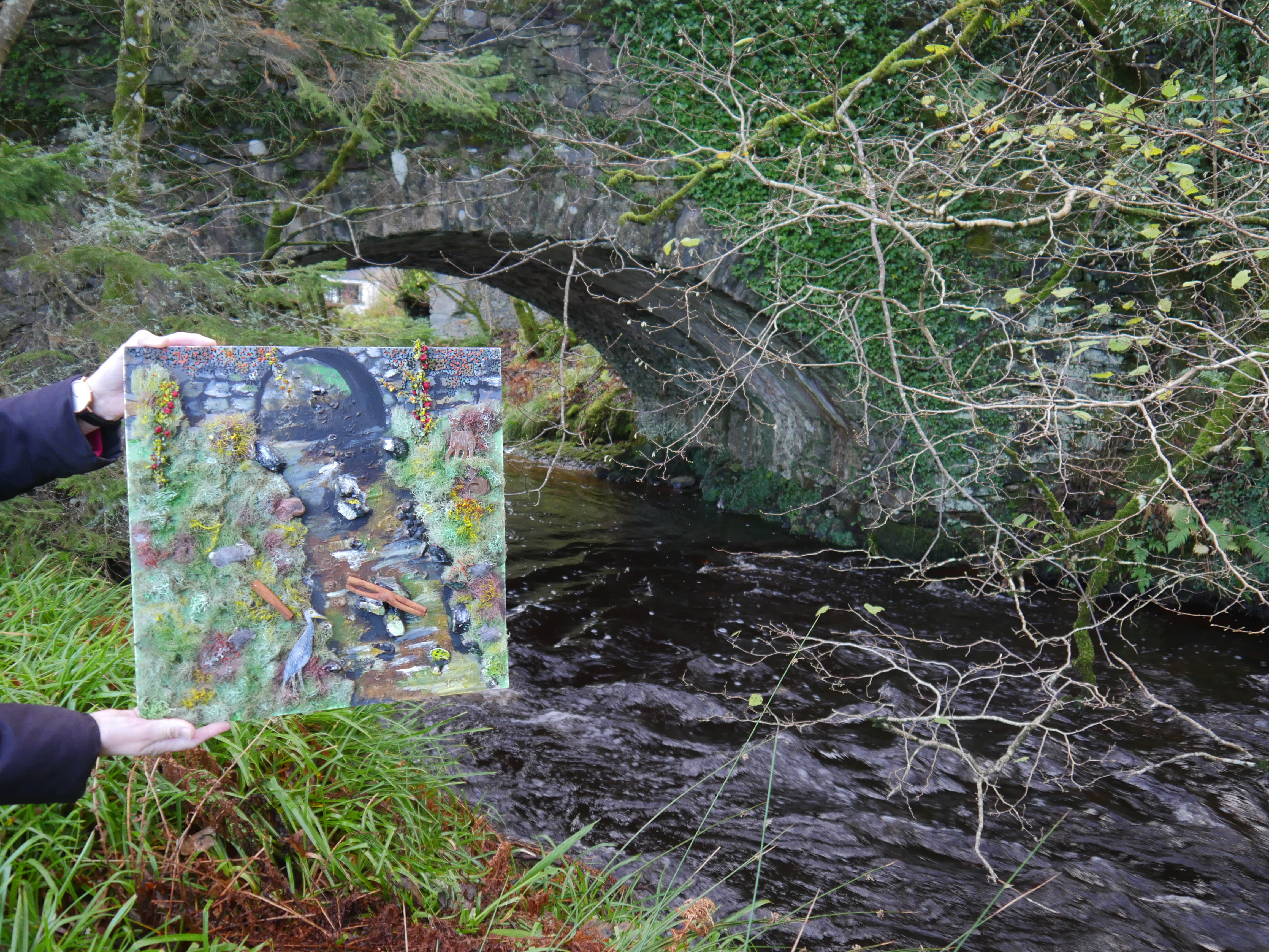 Artwork of nature being held-up in front of small river