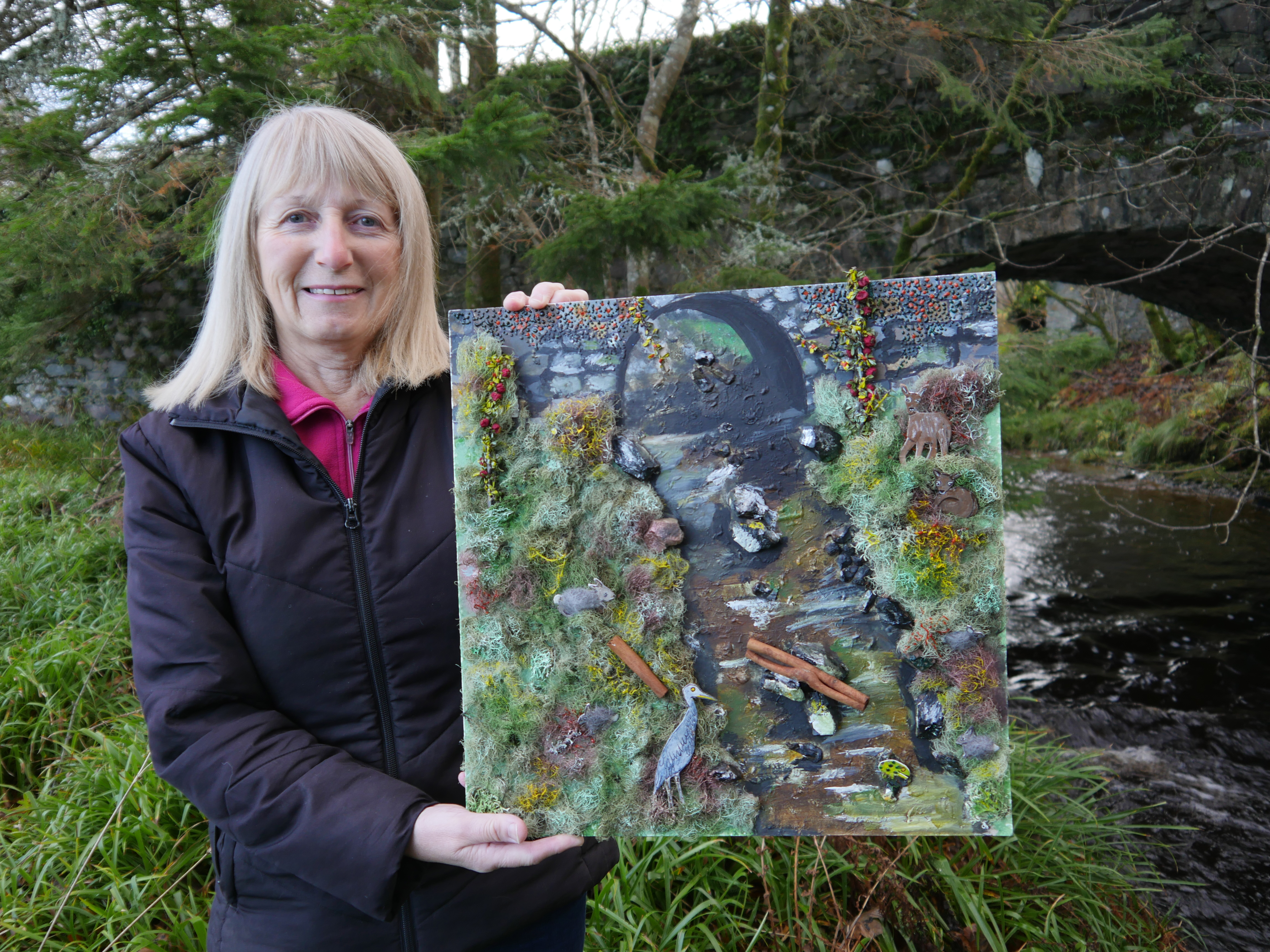 A woman holding up a collage artwork 