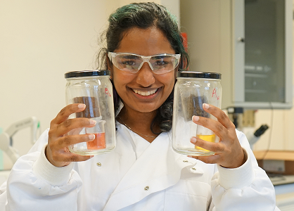 Student in lab holding beakers with experiments