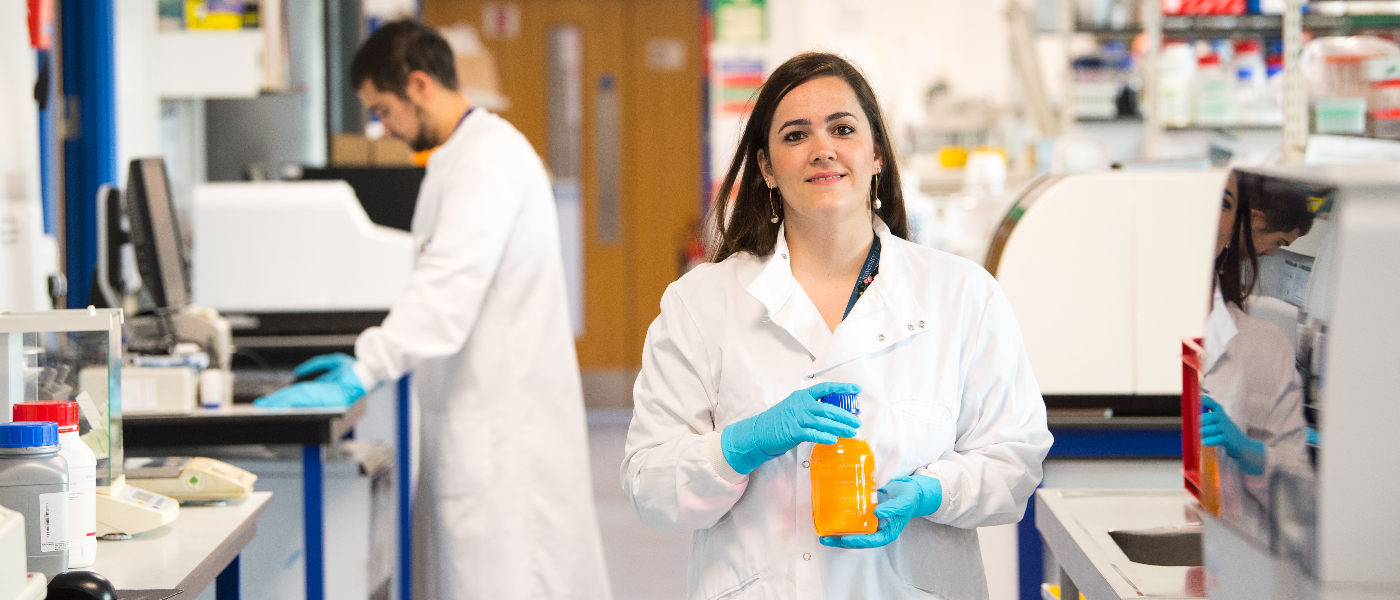 Student holds a chemical jar in a University of Glasgow Laboratory.