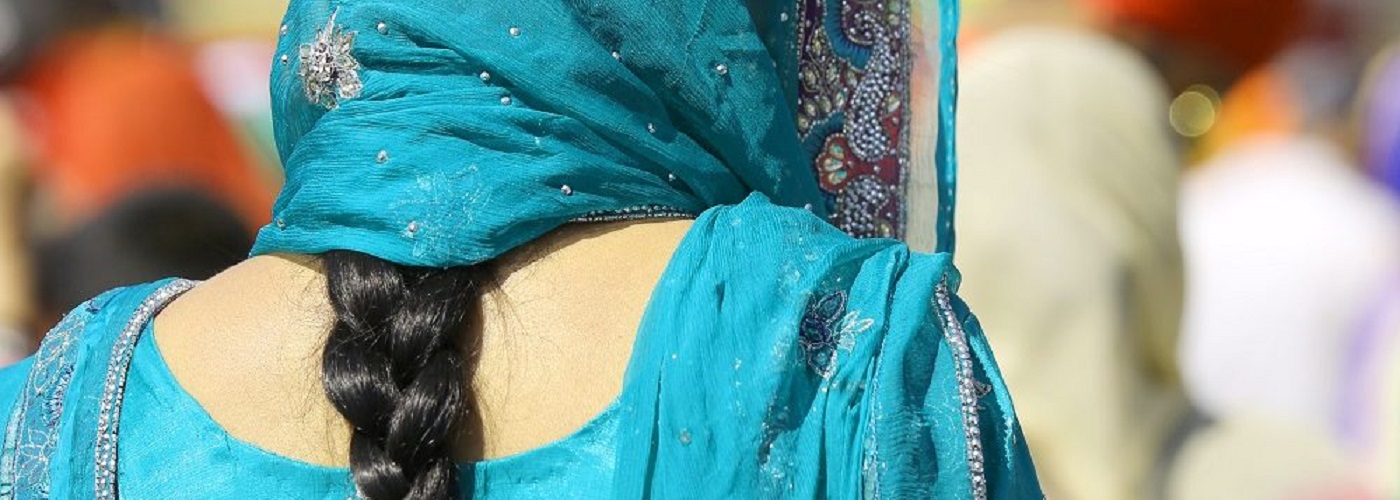 Back view of an Indian woman with her black hair in a plait and wearing in a light blue outfit and scarf over her head. Image credit: ChiccoDodiFC | iStockphoto https://www.istockphoto.com/photo/woman-with-dress-and-long-black-hair-gm954544102-260615928