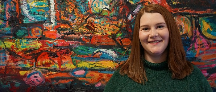 Student standing in front of artwork in Dumfries Campus