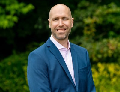 A head and shoulders shot of Professor Scott Border with wide screen background