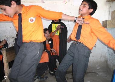 Boys singing and dancing traditional melodies, while girls look on and applaude, Chitral Pakistan, September 2007