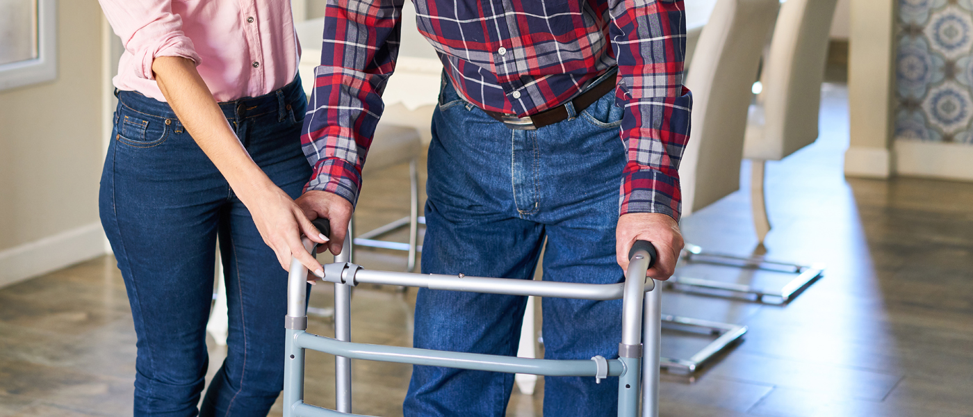 Person using a walking frame supported by a carer