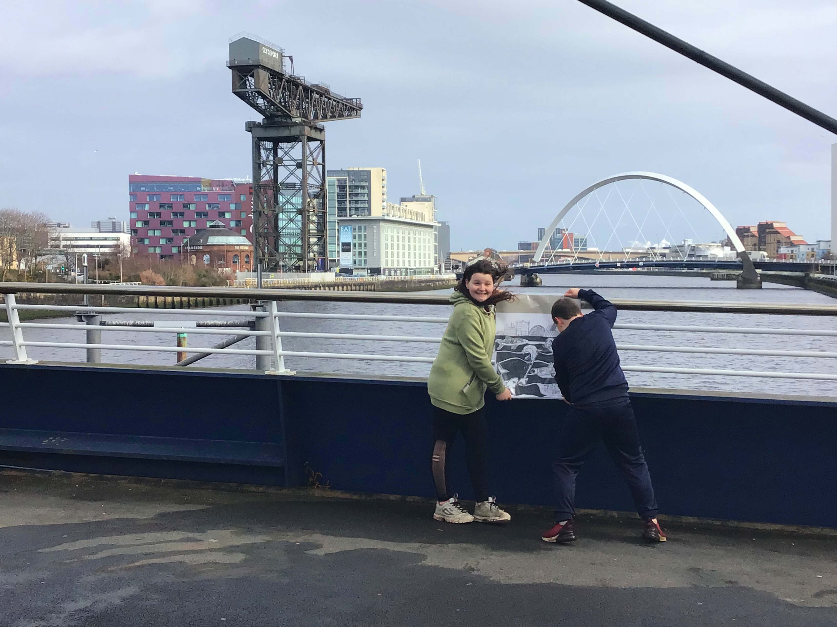 Two children holding an artwork at the river clyde