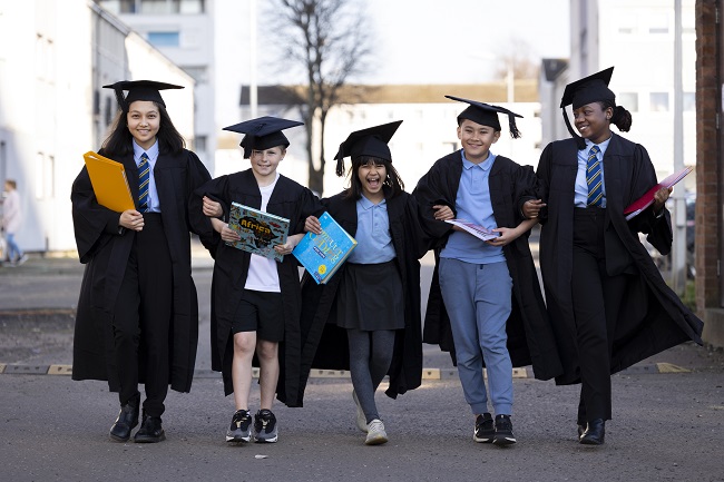 A group of five children wearing graduation gowns link arms at IntoUniversity Maryhill 