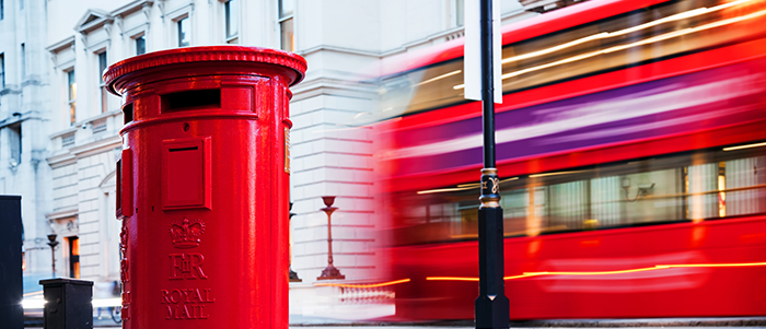Traditional red mail letter box and red bus in motion in London, the UK. Symbols of the city and England