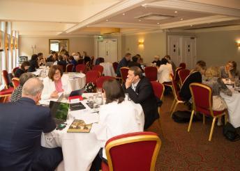 conference venue with delegates chatting around circular tables