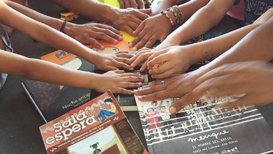 hands placed in a central group over a selection of books