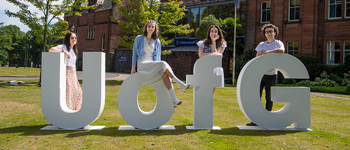 4 students in front of big UofG letters