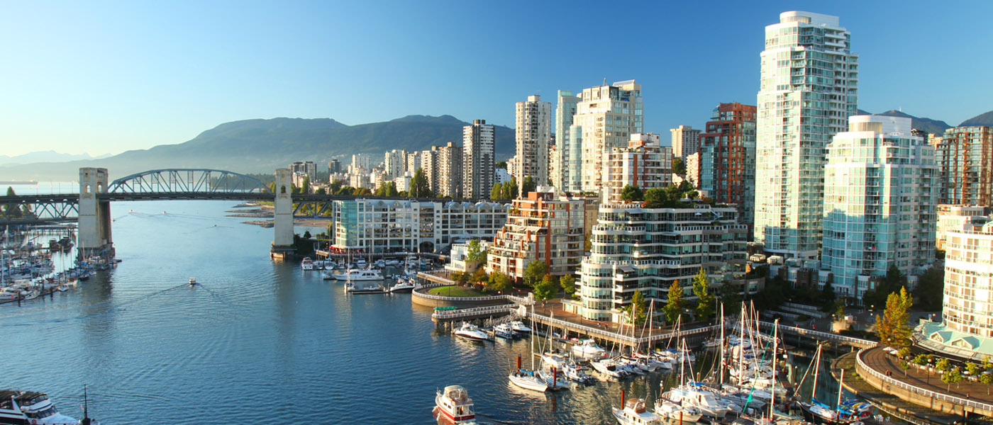 Vancouver cityscape with water and boats in the foreground and mountains in the background