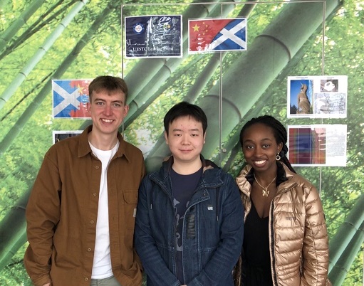 Student Jianzhou Yu standing against a colourful wall, with Student Liaison Interns