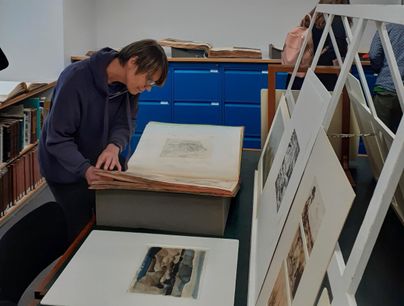 Participant viewing small prints and drawings featuring wetlands at Modern One