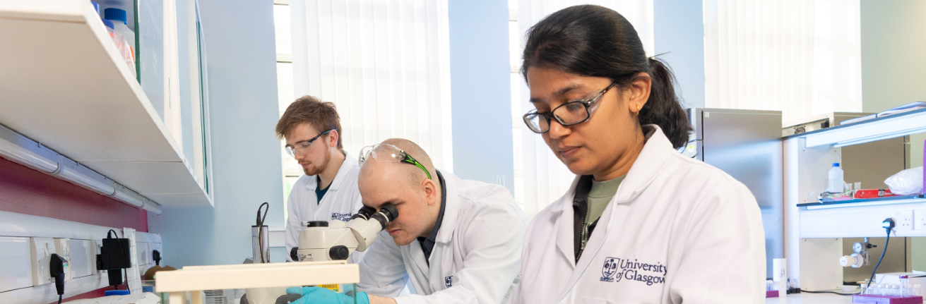 An image showing three students working in the lab, wearing UofG lab coats