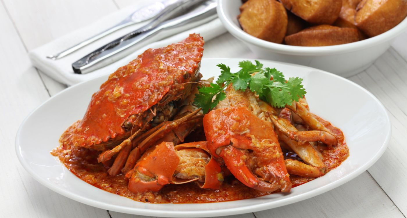 Chilli mud crab cooked in a red chilli sauce with fried mantou buns in the background [Photo: Shutterstock]