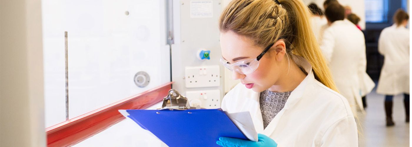 Woman in lab coat reading clipboard 