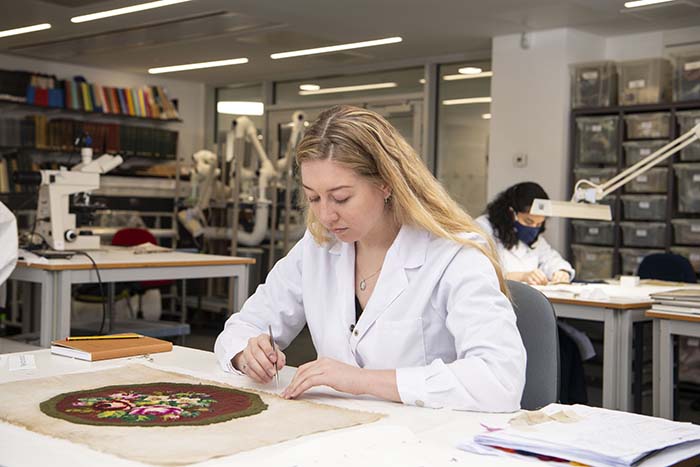 A student sewing a piece of fabric in a lab