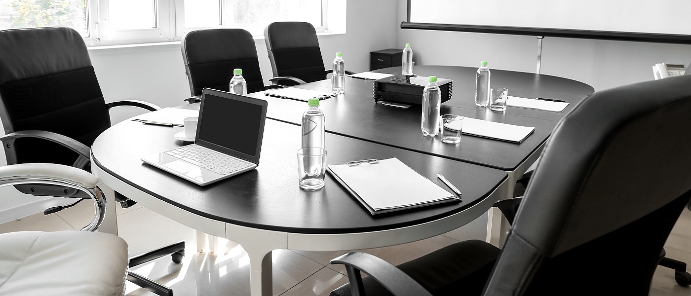 Photo of a conference room with table, chairs, laptop and water