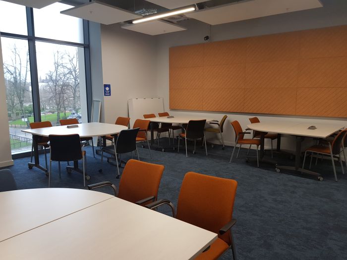 Flat floored teaching room with tables and chairs.