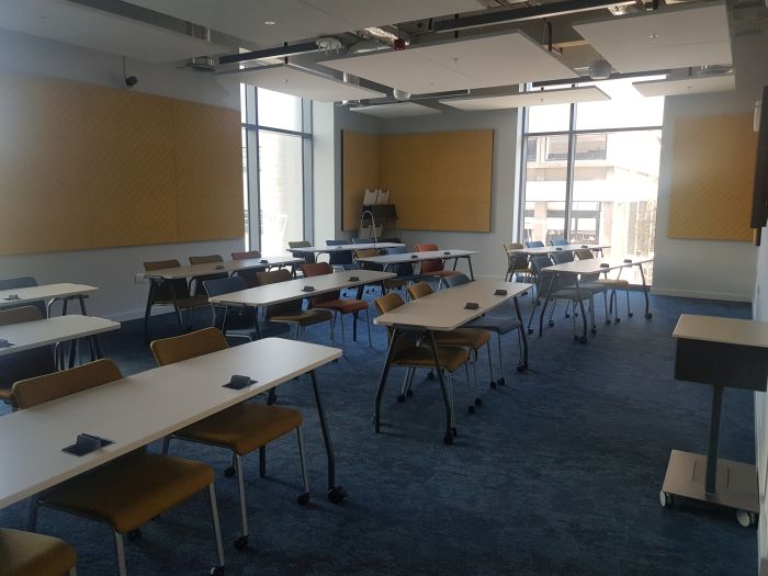 Flat floored teaching room with rows of tables and chairs.