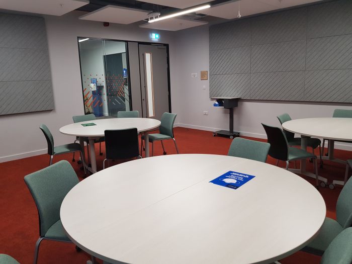 Flat floored teaching room with tables and chairs.