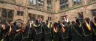 Group of students throw their hats into the air on graduation day at main quad